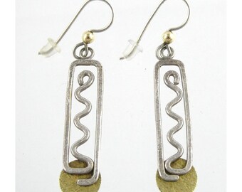 May include: A pair of silver dangle earrings with a gold accent. The earrings feature a rectangular shape with a wavy design inside. The bottom of the earrings have a round gold disc.