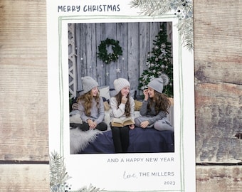 Puede incluir: Una tarjeta de Navidad con una foto de tres chicas con gorros de invierno sentadas en una cama. La tarjeta tiene un borde floral verde y blanco y el texto "Feliz Navidad y un Feliz Año Nuevo Love, The Millers 2023".