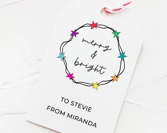 May include: A white gift tag with a black and white illustration of a string of colorful stars in a circle. The text "merry & bright" is written inside the circle. The tag also says "To Stevie From Miranda".