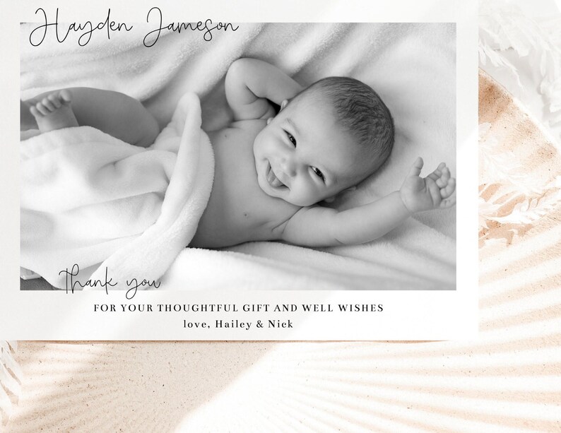 May include: Black and white photo of a baby boy wrapped in a blanket, smiling. The photo is on a white card with the text "Hayden Jameson" and "Thank you" written in cursive. The text "For your thoughtful gift and well wishes" and "love, Hailey & Nick" is also printed on the card.