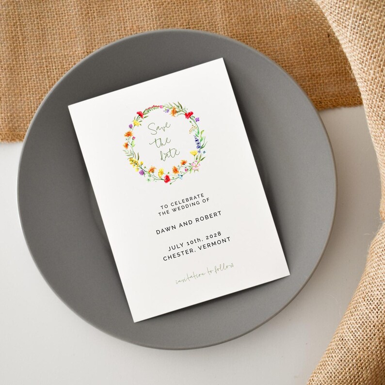 May include: Save the date card with a floral wreath illustration. The text reads "Save the date" and includes the names Dawn and Robert, the date July 10th, 2028, and the location Chester, Vermont.