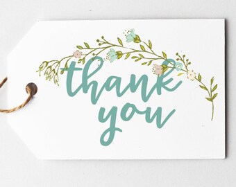 May include: White gift tag with the words "thank you" in teal script. The tag is adorned with a floral design in light blue, pink, and green. A brown string is attached to the tag.