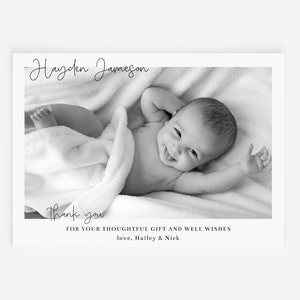 May include: Black and white photo of a baby named Hayden Jameson, lying on a white blanket. The photo is framed with a white border and includes the text "Thank you for your thoughtful gift and well wishes, love, Hailey & Nick".