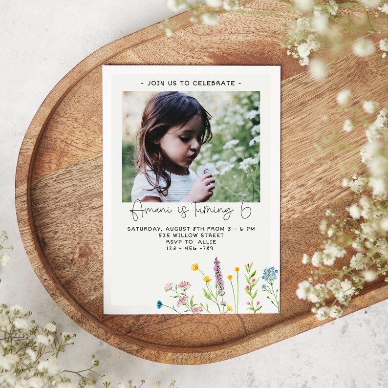 May include: A white invitation card with a photo of a young girl blowing on a dandelion. The text on the card reads "Join us to celebrate - Amani is turning 6. Saturday, August 8th from 3 - 6 PM. 525 Willow Street. RSVP to Allie. 123-456-789". The card is decorated with a watercolor illustration of wildflowers.