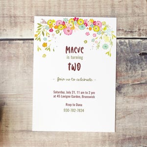 May include: A floral-themed birthday invitation for a girl named Maeve turning two. The invitation features a floral garland with pink, yellow, and green flowers. The text reads "Maeve is turning two. Join us to celebrate - Saturday, July 21, 11 am to 2 pm at 45 Lavigne Garden, Brunswick. Rsvp to Dana 930-782-7834."