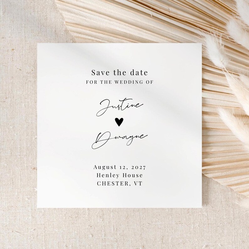 May include: A white wedding invitation card with the text "Save the date" at the top. The names "Justine" and "Dwayne" are written in elegant script, separated by a black heart. The date, location, and year are also included.