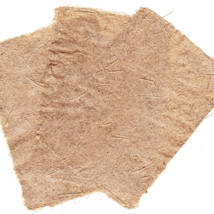 May include: Two pieces of handmade paper with a rough, textured surface. The paper is a light brown color with visible fibers and a slightly torn edge, set against a white background.