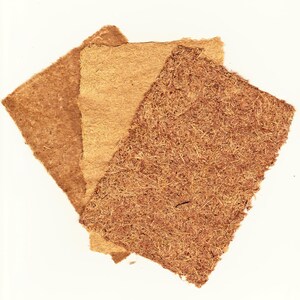 May include: Three textured, square pieces of handmade paper in varying shades of brown. The paper has a rough, fibrous appearance, with visible plant fibers. The colors range from light tan to a darker, reddish-brown, suggesting natural materials.