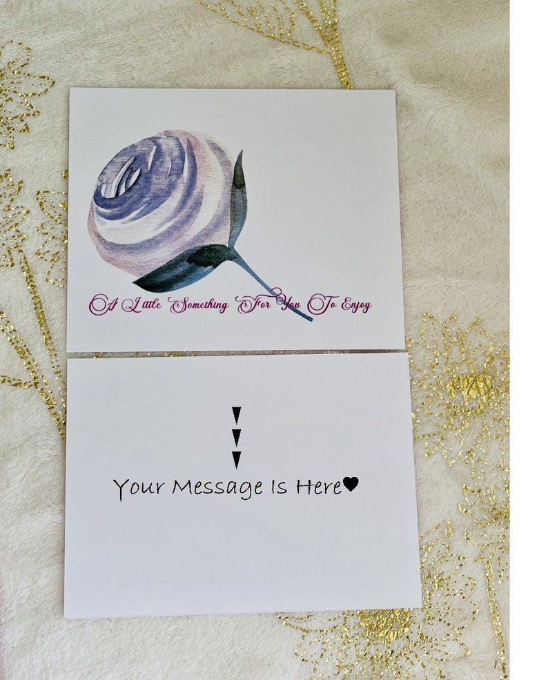 Puede incluir: Una tarjeta blanca con una ilustraci&oacute;n de acuarela de una rosa p&uacute;rpura y blanca. El texto "A Little Something For You To Enjoy" est&aacute; escrito en p&uacute;rpura debajo de la rosa. La parte posterior de la tarjeta tiene el texto "Your Message Is Here" escrito en negro con un s&iacute;mbolo de coraz&oacute;n negro.