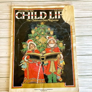 Peut inclure: Un num&eacute;ro vintage de d&eacute;cembre 1926 de Child Life, The Children's Own Magazine, repr&eacute;sentant une sc&egrave;ne de No&euml;l avec deux personnages chantant &agrave; partir d'un livre de musique devant un sapin de No&euml;l d&eacute;cor&eacute;. La couverture du magazine est illustr&eacute;e dans un style color&eacute; avec un fond noir.