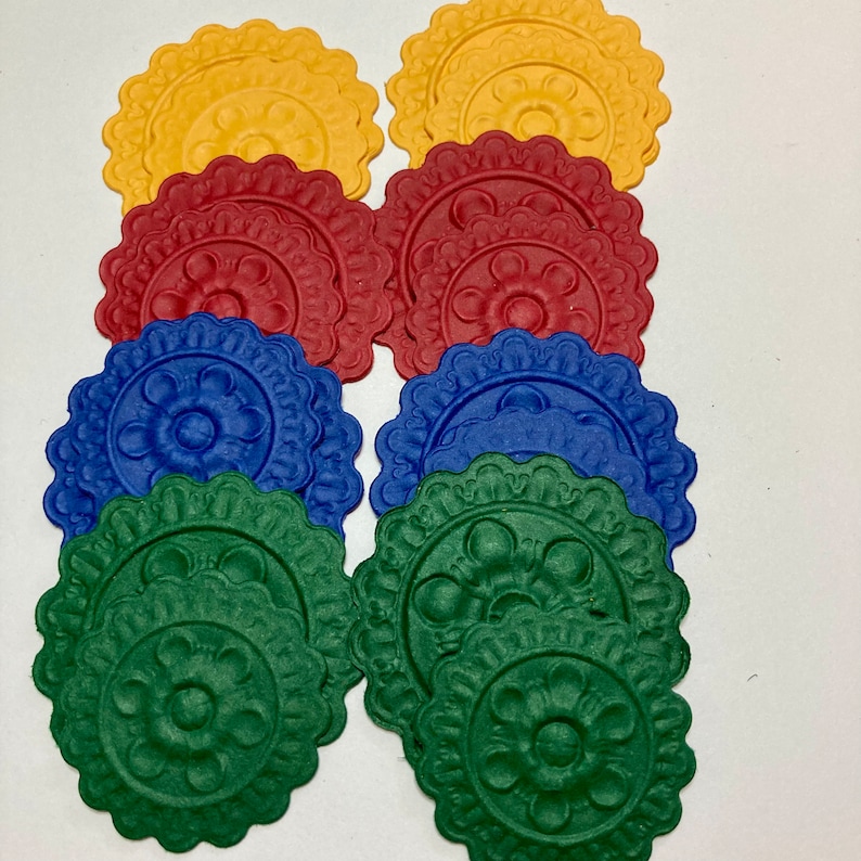 May include: Assortment of paper doilies in four colors: yellow, red, blue, and green. Each doily has a raised, embossed floral design.