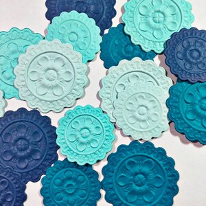 May include: Assortment of decorative paper circles with a raised floral design. The circles are in shades of blue and teal.