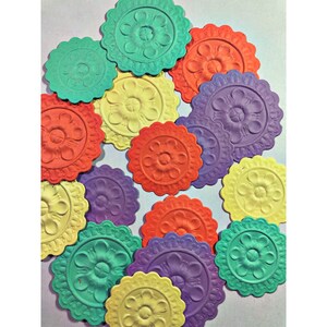 May include: A collection of 13 colorful paper craft embellishments with a floral design. The embellishments are in shades of yellow, green, purple, orange, and red.