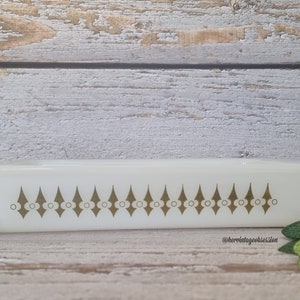 May include: White rectangular baking dish with a gold geometric pattern around the rim. The pattern features a series of diamonds with a circle in the centre of each diamond.