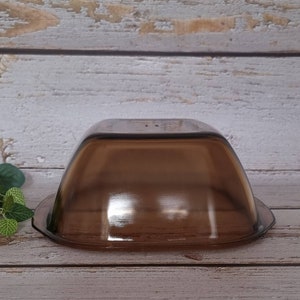 May include: A brown glass baking dish with a square shape and rounded edges. The dish is made of tempered glass and is designed for use in the oven.
