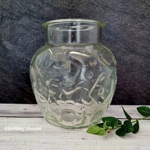 Op de afbeelding: Een glazen pot met een getextureerd, golvend oppervlak. De pot is leeg en heeft een brede opening.