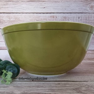Puede incluir: Un tazón grande de mezcla verde hecho de vidrio. El tazón está sentado sobre una superficie de madera.
