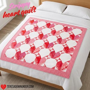 May include: A quilt featuring a repeating pattern of hearts in shades of red and pink, set against a white background. The quilt has a pink border with white polka dots. The text "Strippy heart quilt" is visible in the upper left corner.