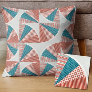 May include: A decorative throw pillow with a geometric pattern of teal and red semi-circles on a white background. The pillow is shown on a light brown surface with a smaller teal and red patterned fabric square in the foreground.
