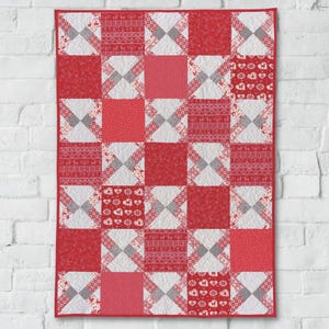 Puede incluir: Una colcha roja y blanca con un diseño de patchwork. La colcha está hecha de cuadrados con diferentes patrones, incluyendo corazones, copos de nieve y formas geométricas.