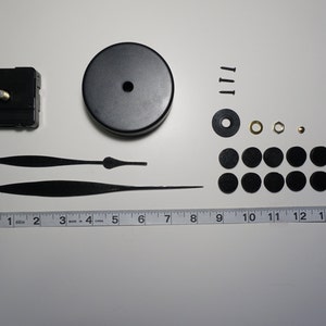 May include: Clock making kit with black hands, a black clock face, black mounting hardware, and a ruler.