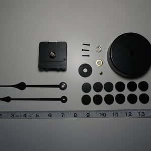 May include: Clock kit with black hands, a black clock face, a black clock base, and 12 black mounting discs.