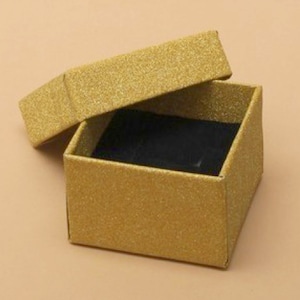 May include: A small, gold glitter gift box with a black velvet interior. The box is open and the lid is resting on top.