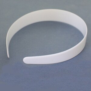 May include: A white plastic headband. The headband is smooth and has a simple design.