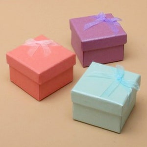 May include: Three small gift boxes with ribbon bows. The boxes are pink, purple, and light blue.