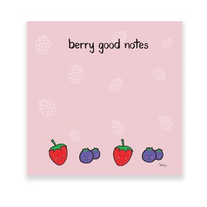 May include: A square notepad with a light pink background featuring the text "berry good notes" at the top. The design includes white line-art berry patterns and a row of colorful cartoon berries with faces at the bottom, including strawberries and blueberries.