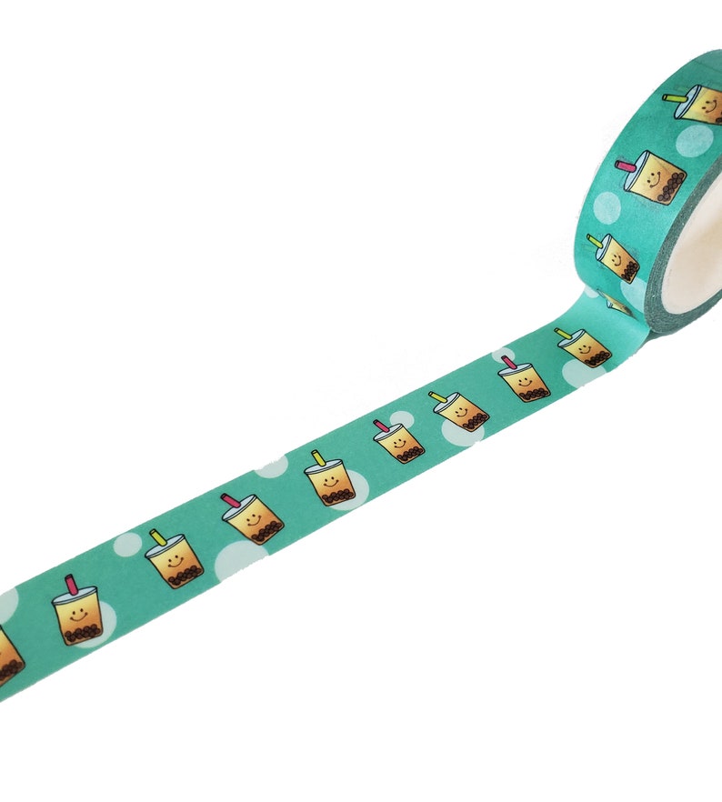 May include: A roll of teal washi tape with a repeating pattern of brown bubble tea cups with smiling faces and pink and green straws. The cups are on a white background with white dots.