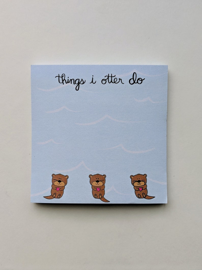 May include: A blue notepad with the text "things i otter do" in black cursive writing. Three brown otters with pink hearts are at the bottom of the notepad.