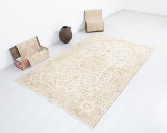 May include: A vintage cream-coloured rug with a floral pattern. The rug has a distressed look and is made of natural fibres.