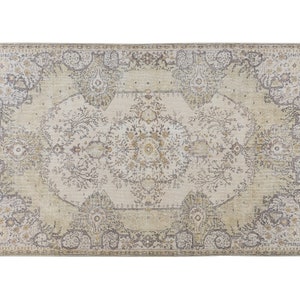 May include: Rectangular area rug with an intricate, faded floral pattern in cream, beige, and gray tones. The rug features a central medallion design and a border with stylized floral motifs, creating a vintage aesthetic.