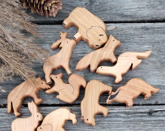 May include: A set of wooden animal figurines, including a bear, a deer, a squirrel, a badger, a rabbit, and a beaver. The figurines are hand-carved and painted in natural wood tones.