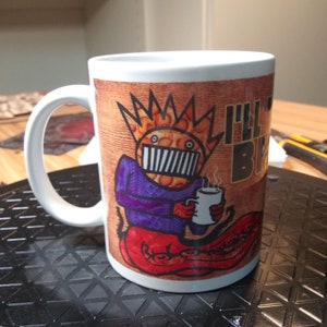 Può includere: Tazza in ceramica bianca con un personaggio dei cartoni animati che tiene una tazza di caffè. Il personaggio indossa una camicia viola, pantaloni rossi e una corona. Il testo "I'll Be Back" è visibile sulla tazza.