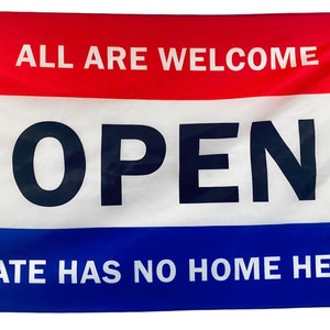 May include: A red, white, and blue flag with the words "ALL ARE WELCOME" in white on the red stripe, "OPEN" in black on the white stripe, and "HATE HAS NO HOME HERE" in white on the blue stripe.