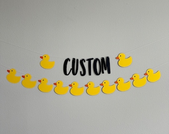 May include: A yellow rubber ducky banner with the word "CUSTOM" in black letters. The banner is strung together with yellow rubber duckies.