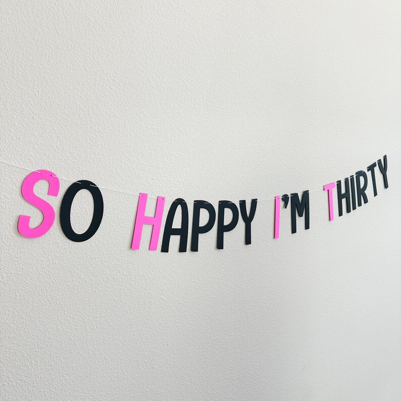 May include: Pink and black paper banner with the text "SO HAPPY I'M THIRTY".