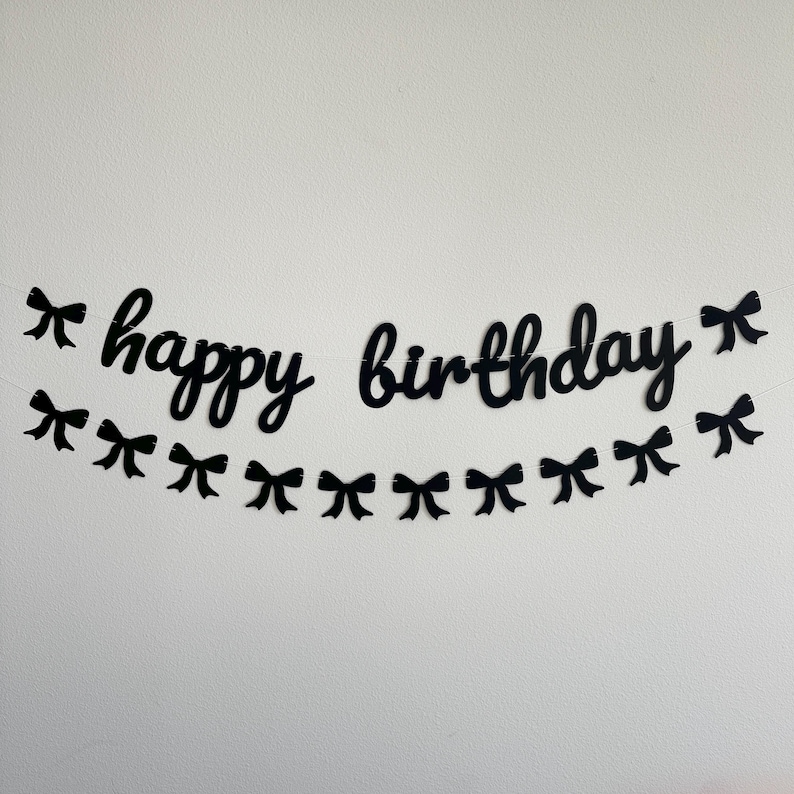 Pode incluir: Faixa de feliz anivers&aacute;rio em preto e branco com la&ccedil;os pretos. A faixa &eacute; feita de papel e &eacute; enfiada com barbante.