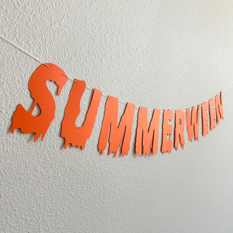 Puede incluir: Pancarta de papel naranja con las palabras "Summerween" en un estilo de fuente que gotea.