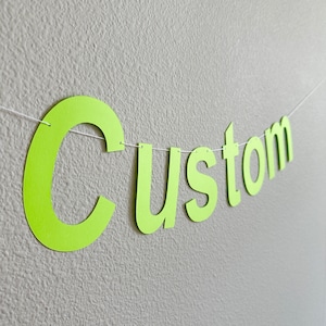 May include: A lime green paper banner with the word "Custom" spelled out in large letters.
