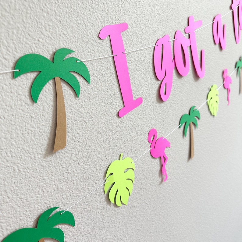 Puede incluir: Guirnalda decorativa con la frase rosa "I got a vibe", adornada con palmeras verdes, flamencos y hojas tropicales. Ideal para una fiesta o evento, la guirnalda est&aacute; ensartada en una cuerda blanca.