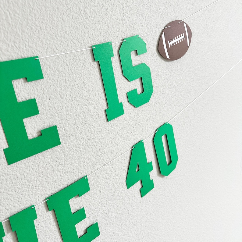 Puede incluir: Pancarta verde y blanca con el texto "He is 40" y una pelota de f&uacute;tbol marr&oacute;n.