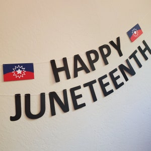 May include: A black banner with the words "Happy Juneteenth" in large, bold letters. Two small flags with a red, white, and blue star design are hanging from the banner.