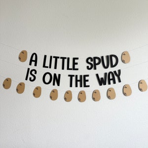 May include: A brown and black banner with the text "A little Spud is on the way" and brown potato-shaped decorations.