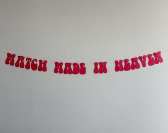 May include: A pink paper banner with the text "MATCH MADE IN HEAVEN" in a retro font.