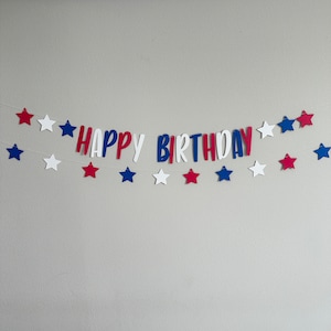 May include: Red, white and blue paper banner with the words "Happy Birthday" and stars.