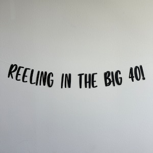 May include: Black and white banner with the text "REELING IN THE BIG 40!" hanging on a white wall.