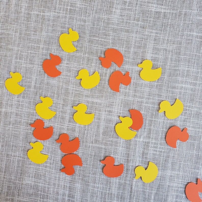 May include: A collection of yellow and orange rubber duckies scattered on a textured fabric surface.